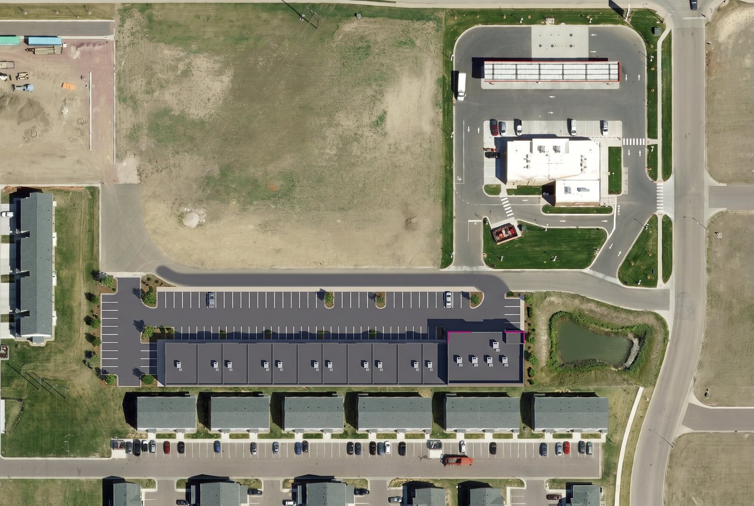 Aerial rendering of the building drawn to scale on its lot: eleven suites and the Just For Kix end, one row of head-in parking, the west lot, the detention pond to the east and townhomes to the south