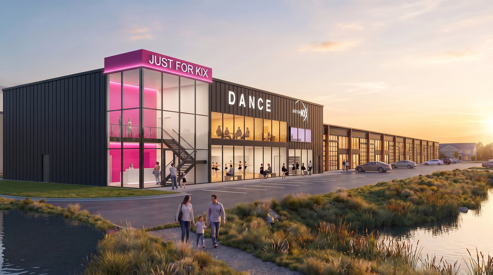 The Just For Kix end of a Next To Kix building at golden hour: a two-story glass entry with dancers visible through the lobby glass and parents in the viewing room above